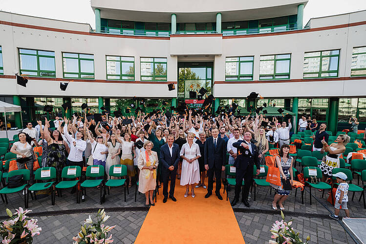 grupa ludzi pozuje do zdjęcia przed budynkiem